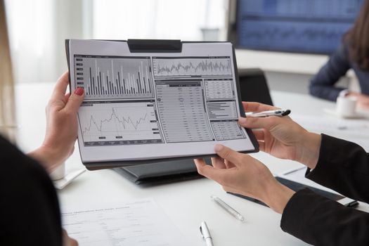 Professionals reviewing data charts on paper during a business meeting.