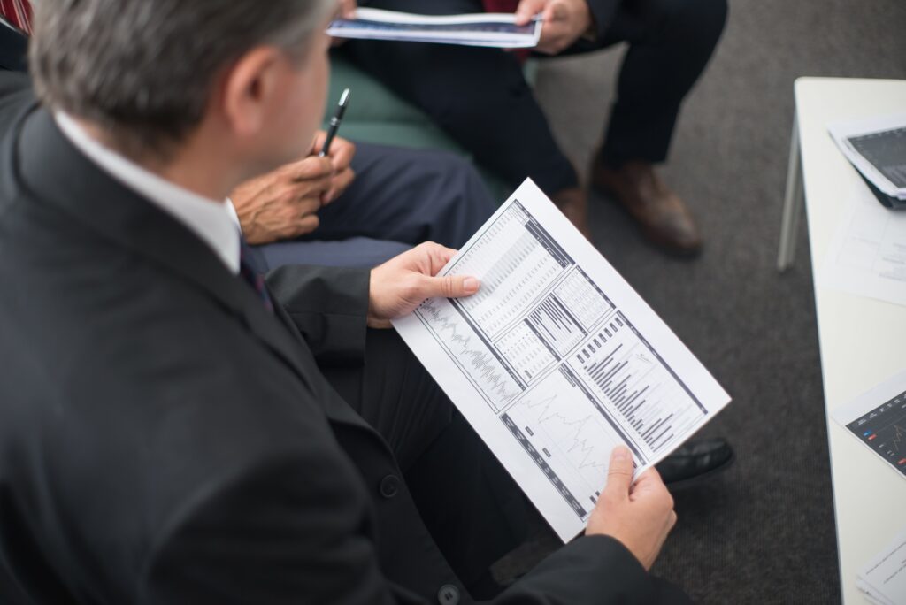 Two businessmen analyze financial documents during a meeting, focusing on data trends and performance.